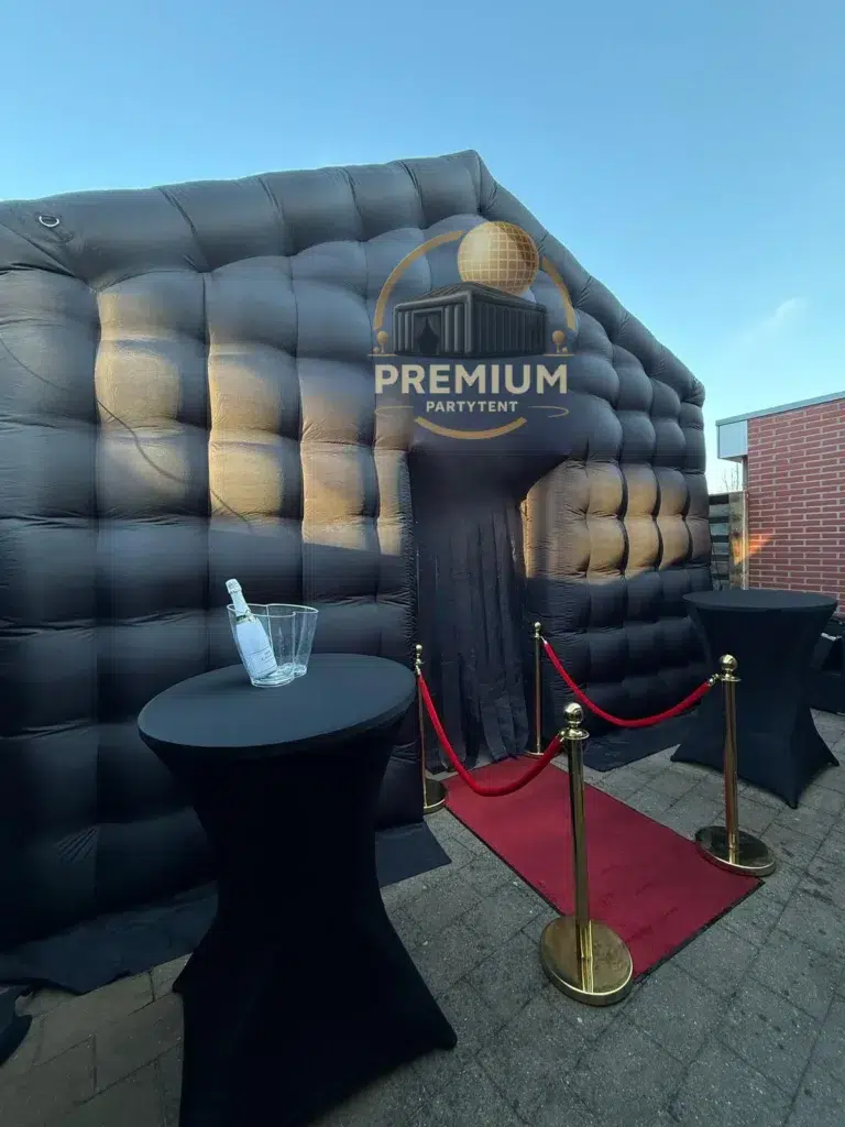 Opblaasbare nachtclub in een tuin met rode loper en afzetpalen