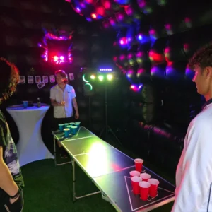 Binnenin de opblaasbare feesttent met bierpongtafel en gekleurde lichten