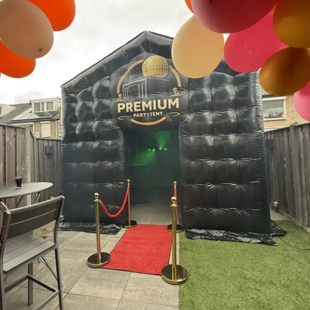 Opblaasbare tent op een betegeld terras met rode loper en gouden afzetpalen