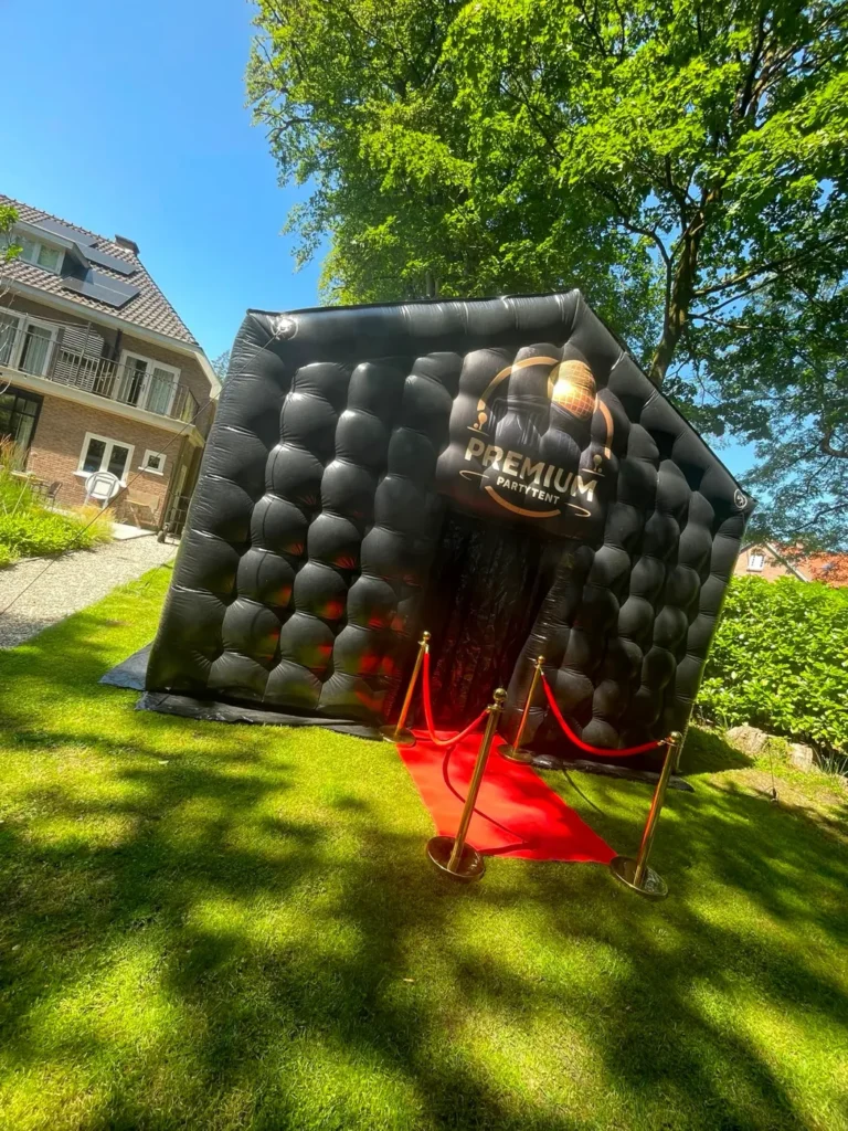 Tent op het gras onder de bomen met rode loper naar de ingang