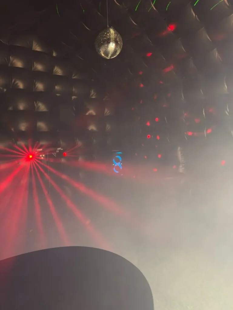 Binnenkant van de discotent met spiegelbol, laserlicht en rook tijdens een feest