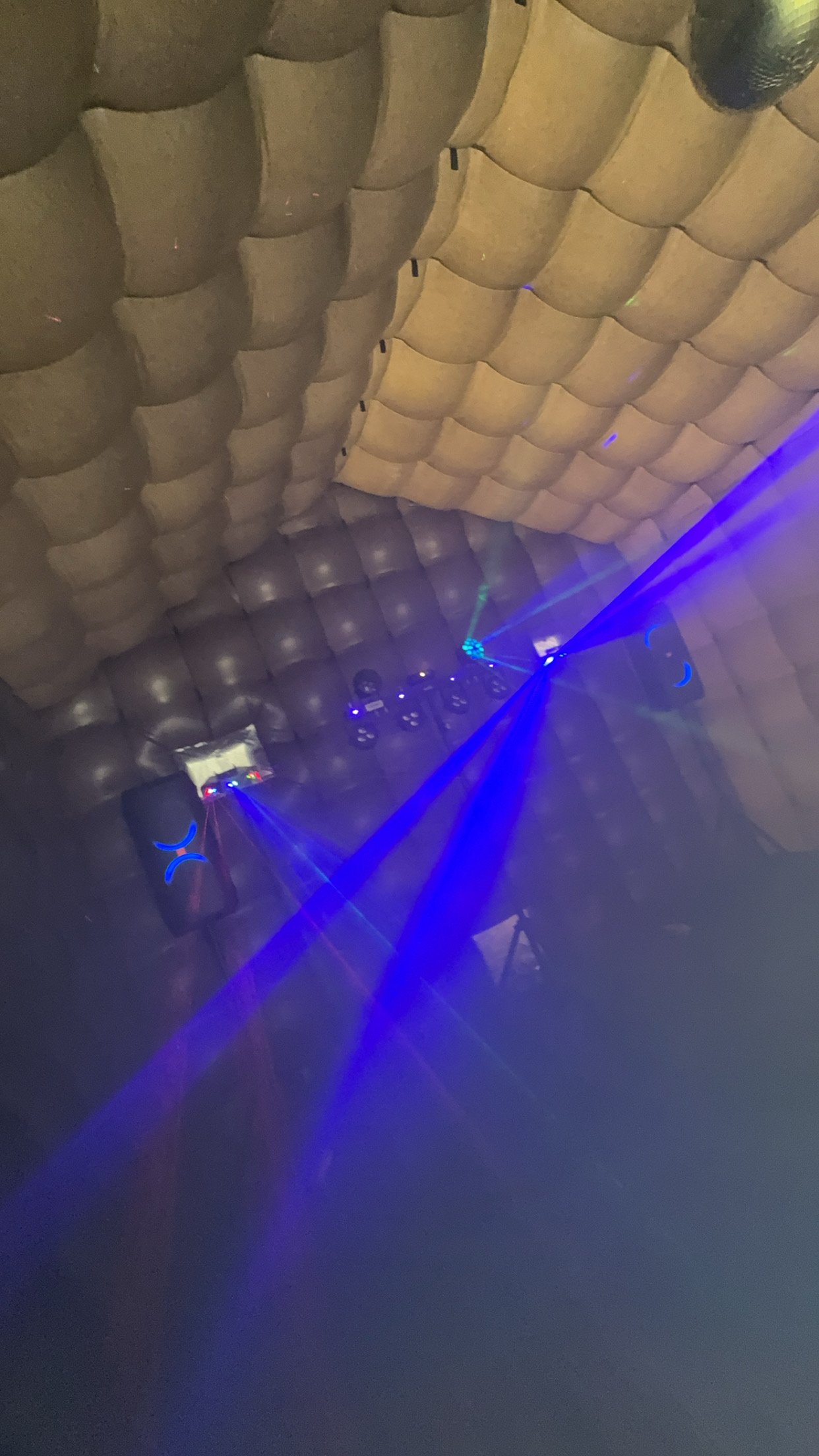Binnenkant van de discotent met daglicht op het gewatteerde dak en blauwe laserbundels eronder